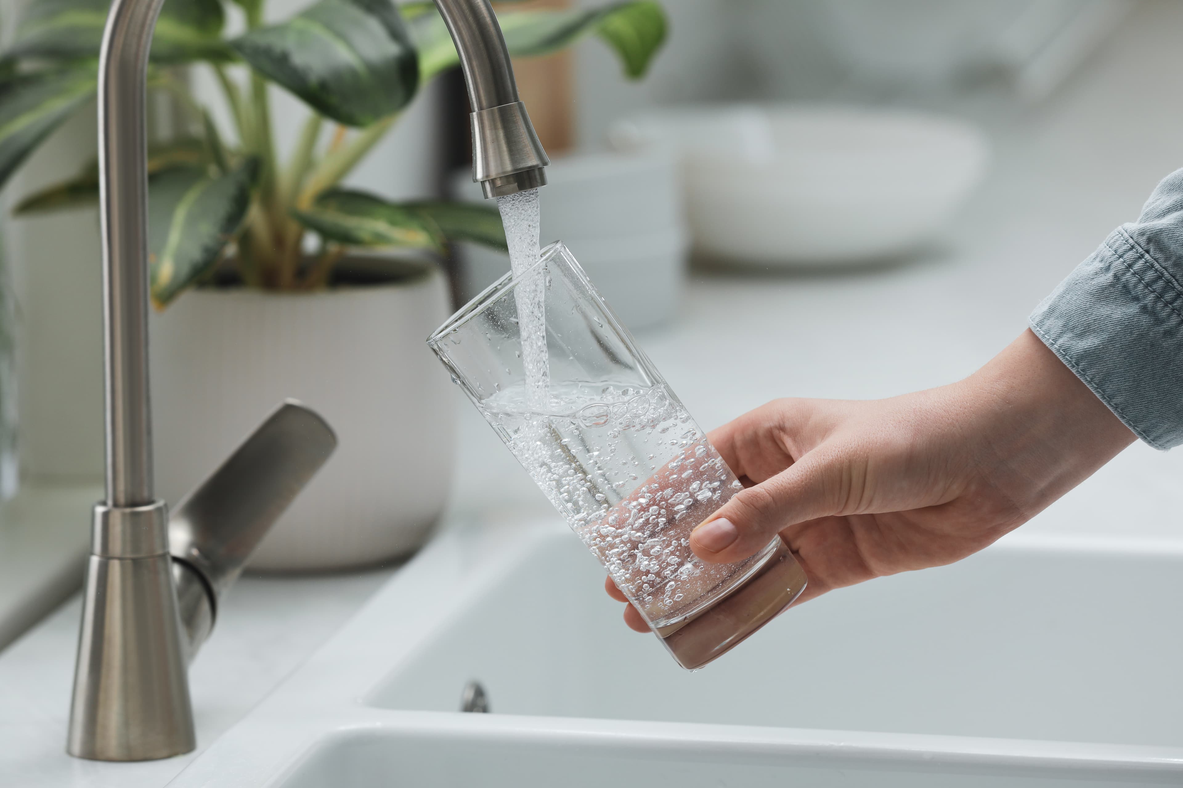 Filtered water pouring from a kitchen tap into a clear glass